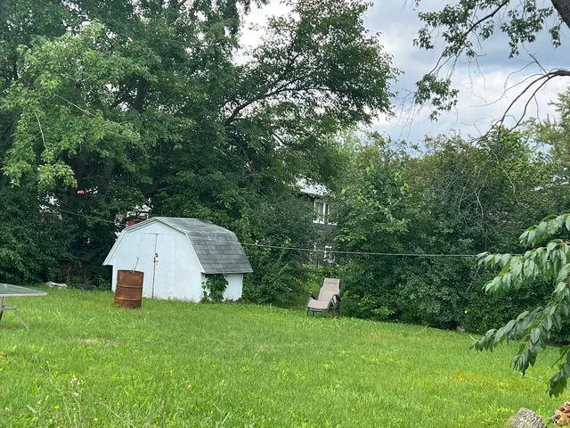 a view of a tiny house with a yard and sitting area