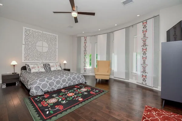 a bedroom with a bed window and walk in closet with wooden floor