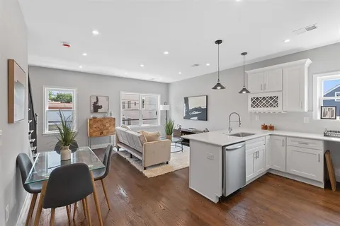 a view of living room kitchen with stainless steel appliances granite countertop furniture and wooden floor