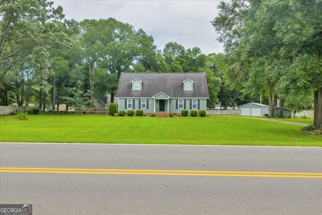 a view of house with a big yard and large trees