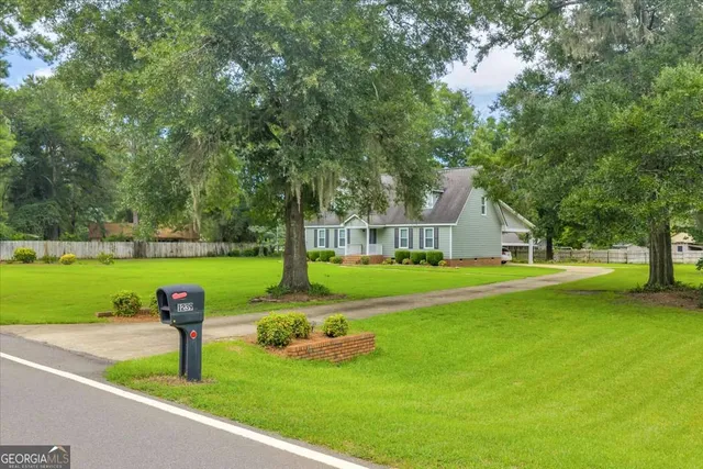 a front view of a house with garden and trees
