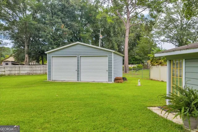 a backyard of a house with plants and large tree