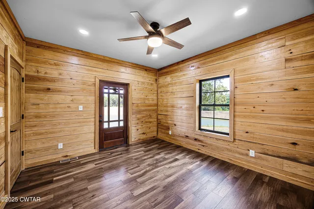 a view of empty room with wooden floor and fan