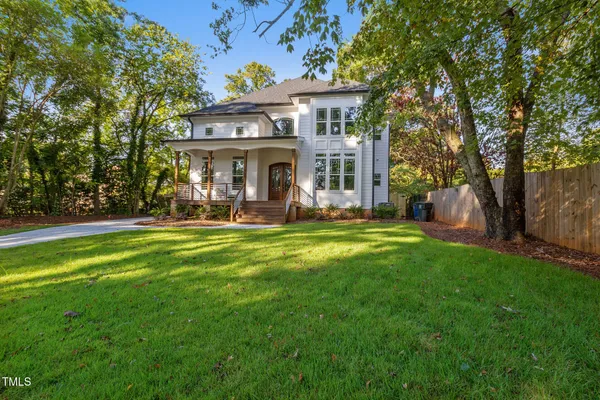 a front view of a house with garden and trees