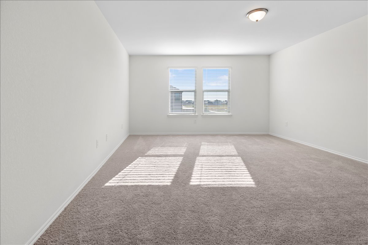18501 Spotted Eagle Lane Elgin, TX 78621 - Photo 34 of 40 A spacious room offers comfortable carpeting and natural light through two well-placed windows.