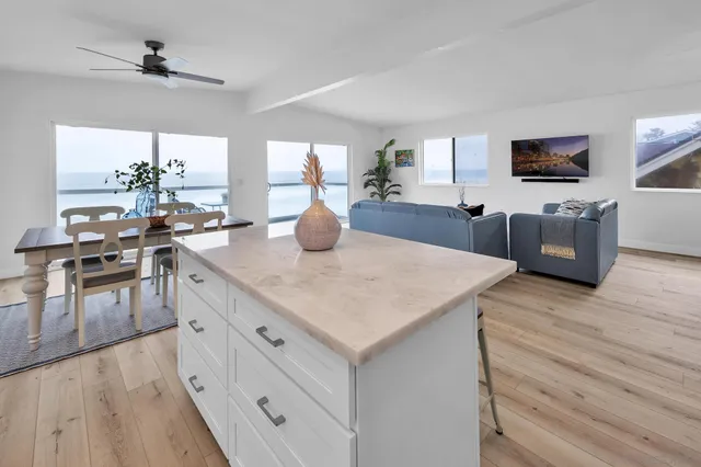 a kitchen with stainless steel appliances kitchen island granite countertop a sink dishwasher a dining table and chairs with wooden floor