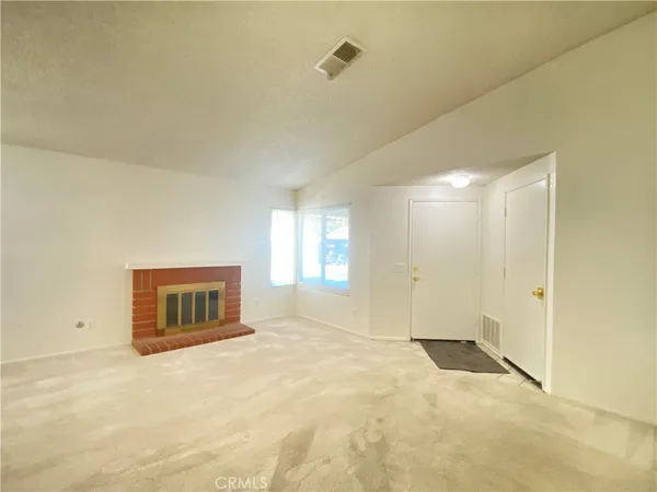 a view of an empty room with a fireplace and a window