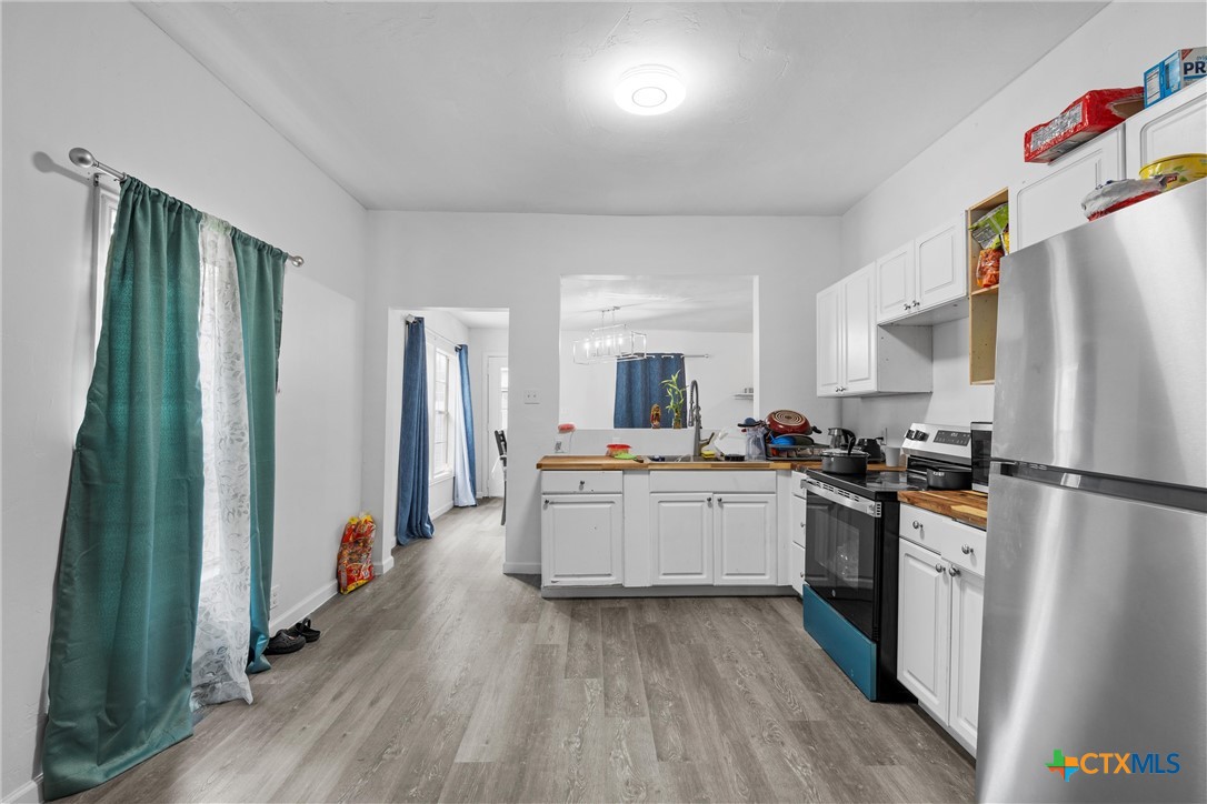 1211 South 17th Street Temple, TX 76504 - Photo 6 of 21 a kitchen with sink a refrigerator and white cabinets