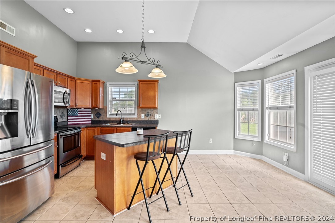176 Clearbrook Place Raeford, NC 28376 - Photo 12 of 36 a kitchen with stainless steel appliances granite countertop a stove top oven a refrigerator a sink and a dining table with white cabinets