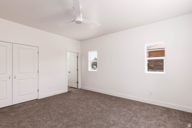 51 West 500 South Monroe, UT 84754 - Photo 19 of 41 Interior room featuring a white ceiling fan, two windows providing natural light, white walls, and dark carpeting