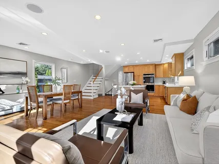 a living room with furniture kitchen view and a large window
