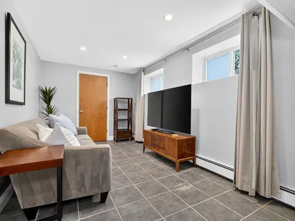 a living room with furniture a flat screen tv and a refrigerator