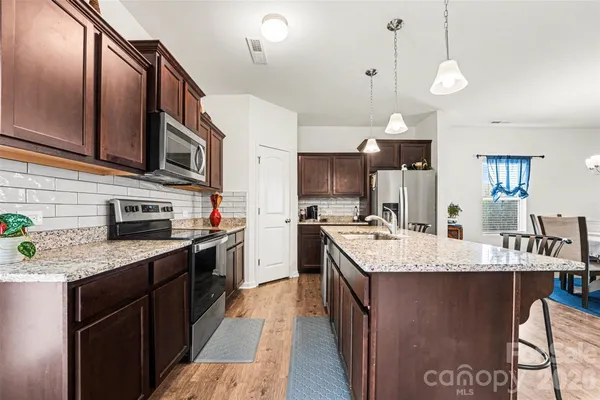 a large kitchen with stainless steel appliances granite countertop a sink a stove and cabinets