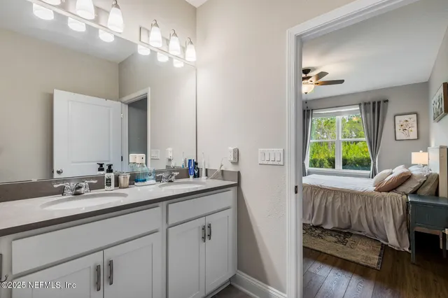 a en suite bathroom with a double vanity sink large mirror and a window