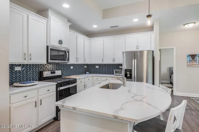 a kitchen with white cabinets and stainless steel appliances