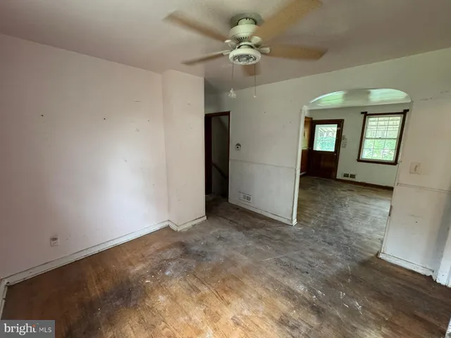 an empty room with chandelier fan and windows