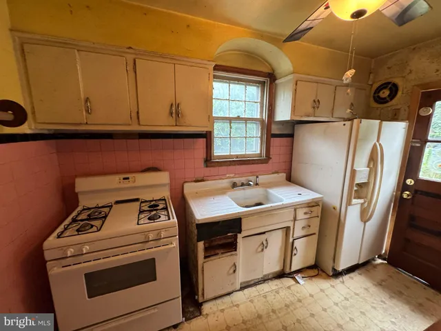 a kitchen with stainless steel appliances granite countertop a stove a refrigerator and a sink with wooden cabinets