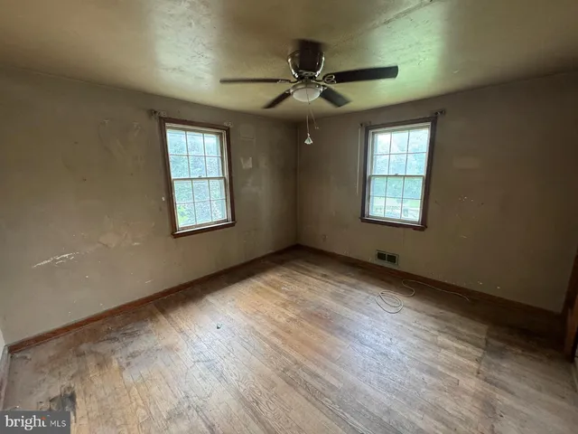 a view of an empty room with a window and wooden floor