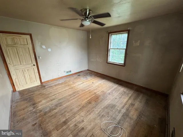 an empty room with windows and fan