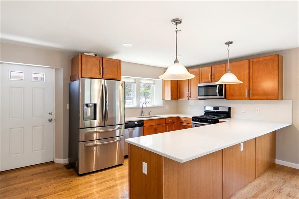 6 Bates Street, Unit A Devens, MA 01434 - Photo 15 of 41 a kitchen with stainless steel appliances a stove a refrigerator a sink a center island and wooden floor