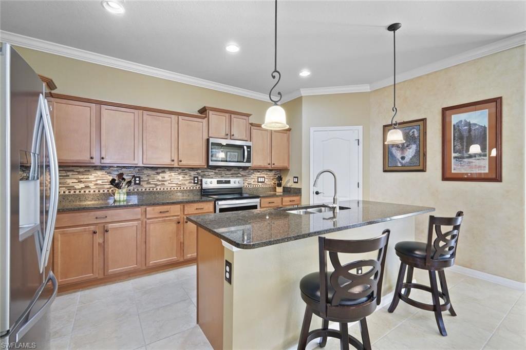 21025 Bella Terra Boulevard Estero, FL 33928 - Photo 4 of 35 a kitchen with stainless steel appliances granite countertop a stove a sink dishwasher a dining table and chairs with wooden cabinets