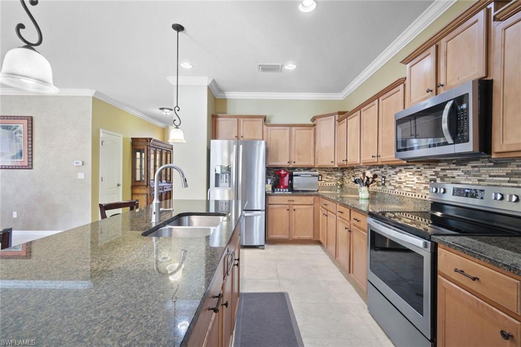 21025 Bella Terra Boulevard Estero, FL 33928 - Photo 5 of 35 a kitchen with stainless steel appliances granite countertop a sink a stove top oven a refrigerator cabinets and chairs