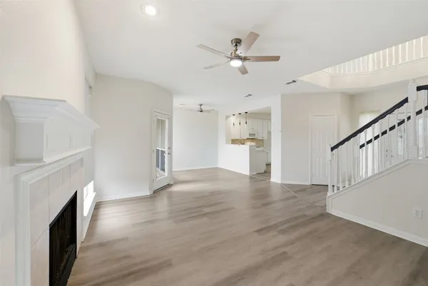 a view of an empty room with wooden floor and a fireplace