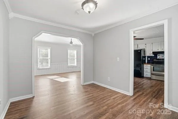 a view of a kitchen and an empty room with wooden floor