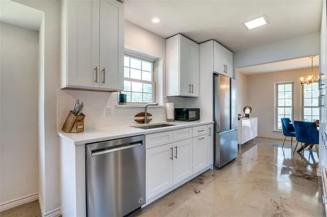 a kitchen with stainless steel appliances granite countertop a refrigerator a sink dishwasher a dining table and chairs with wooden floor