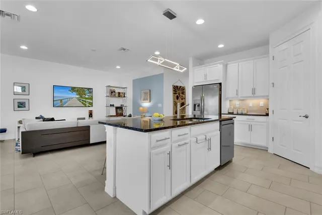 a large white kitchen with kitchen island a sink a counter top space and appliances