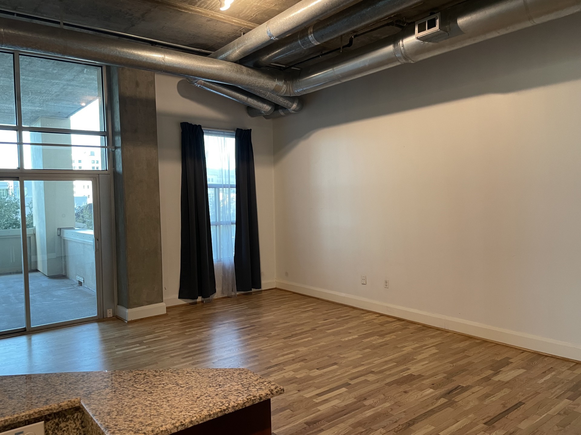 1401 Calumet Street, Unit 300 Houston, TX 77004 - Photo 11 of 31 This modern loft features an open layout with wood flooring, exposed ductwork, and large windows leading to a balcony, offering ample natural light and an industrial vibe.