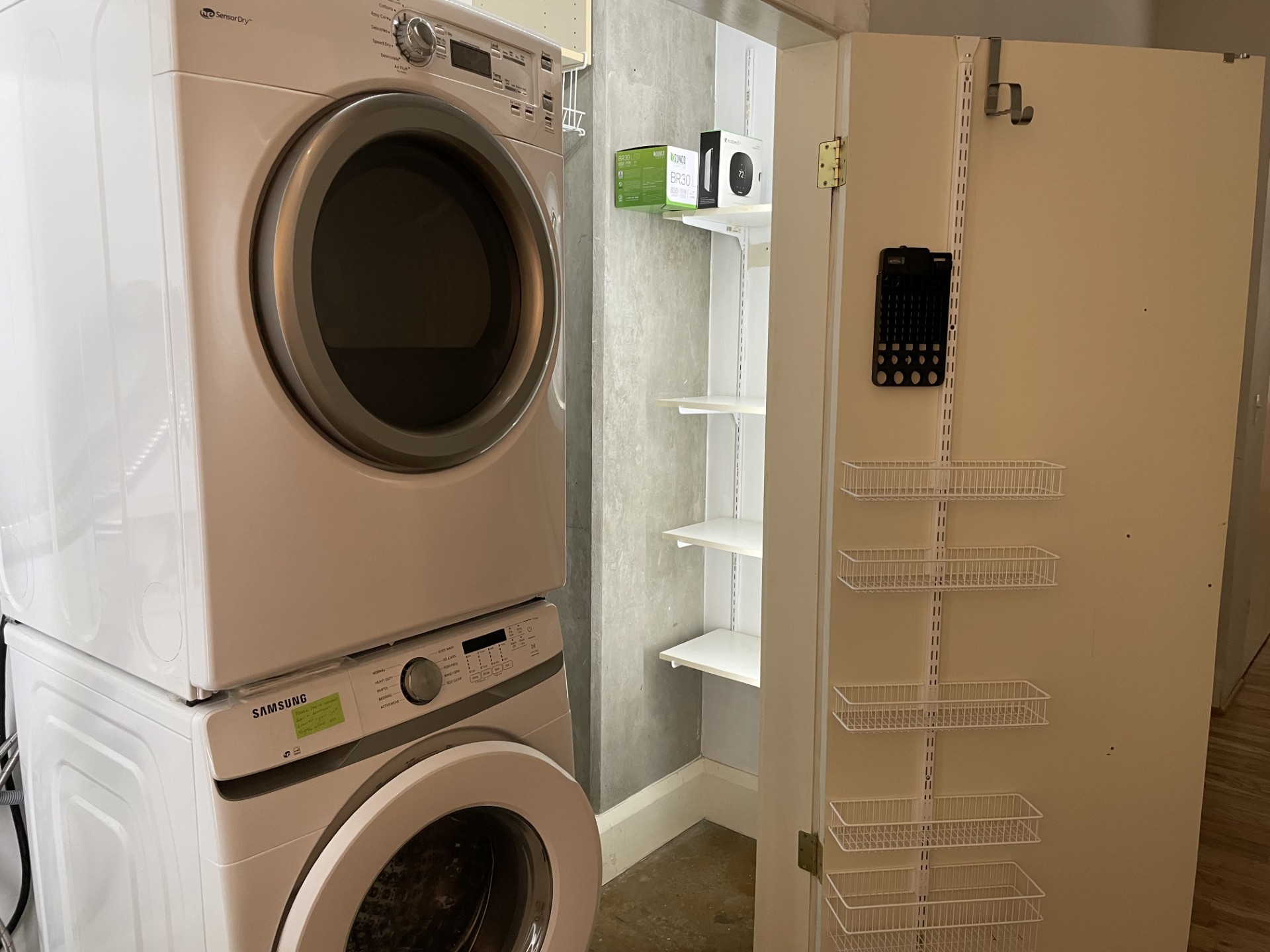 1401 Calumet Street, Unit 300 Houston, TX 77004 - Photo 25 of 31 This photo shows a compact laundry area with a stackable washer and dryer. Adjacent is a storage closet with open shelving and a door-mounted organizer, ideal for maximizing space and convenience.