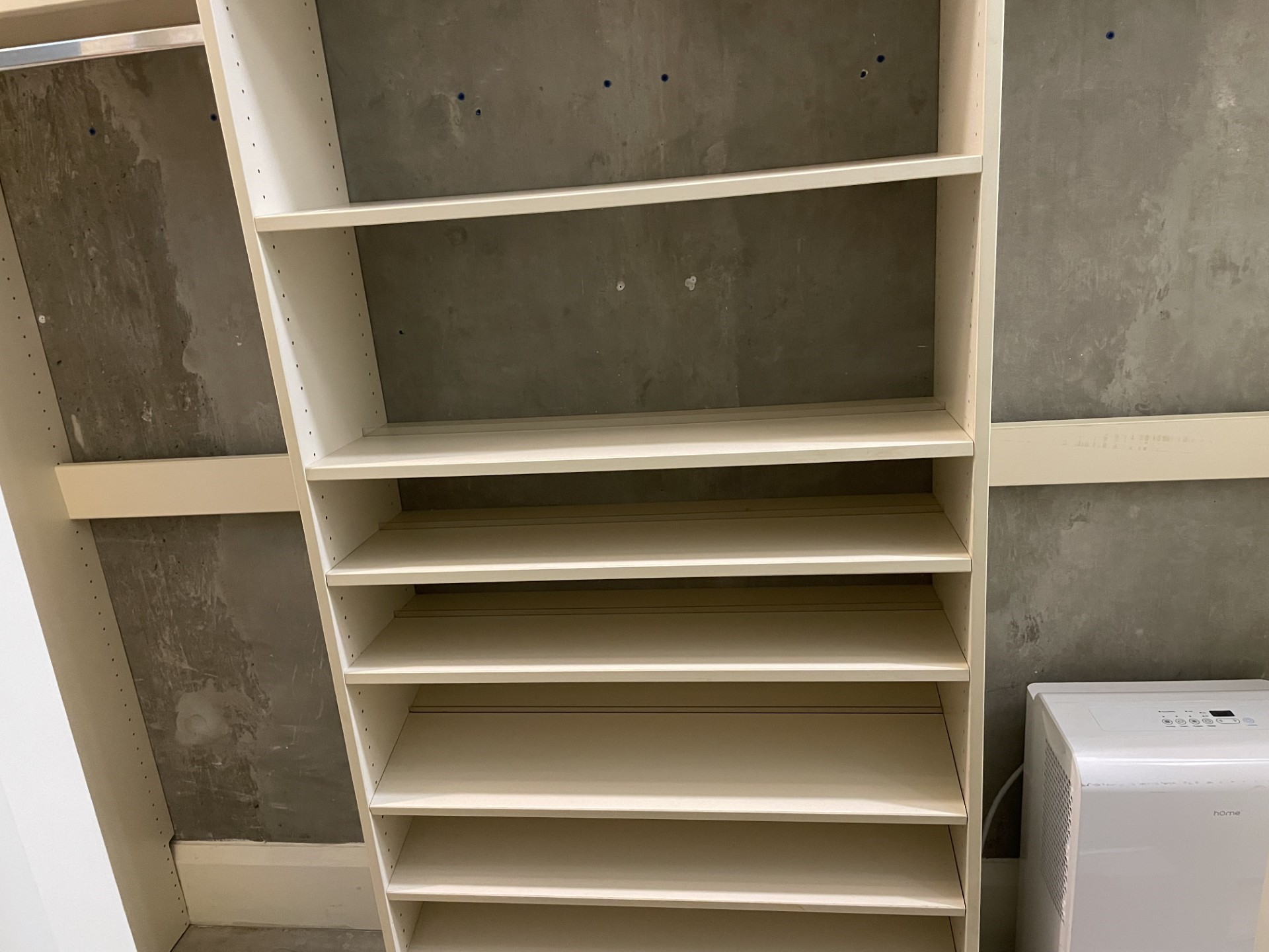 1401 Calumet Street, Unit 300 Houston, TX 77004 - Photo 28 of 31 This photo shows a room with a built-in shelving unit against a concrete wall, ideal for storage. A dehumidifier is also present, suggesting the space may be used for keeping items dry and organized.