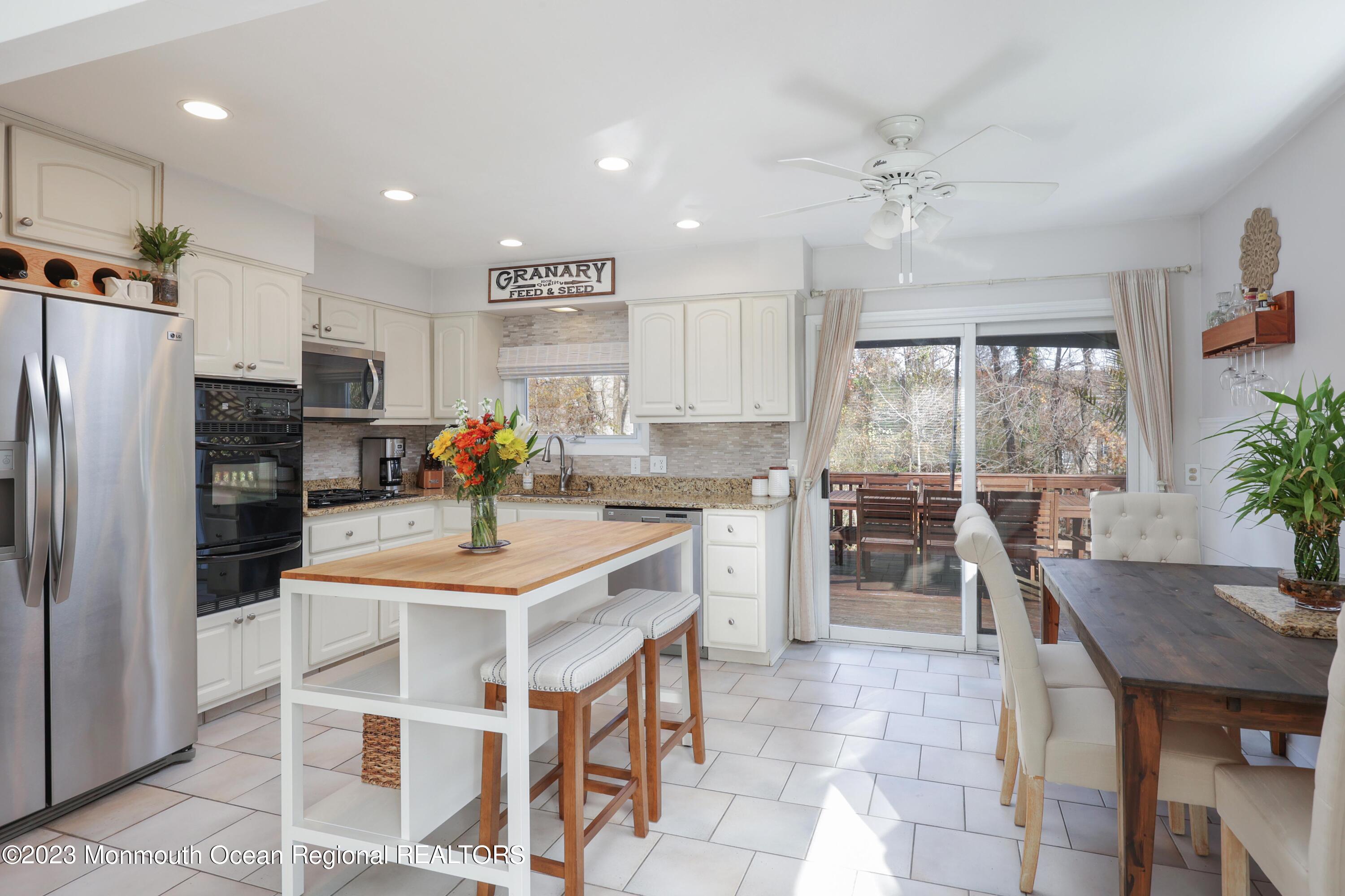 1208 Oak Road Manasquan, NJ 08736 - Photo 15 of 52 a kitchen with stainless steel appliances granite countertop a stove a refrigerator a sink a dining table and chairs with wooden floor