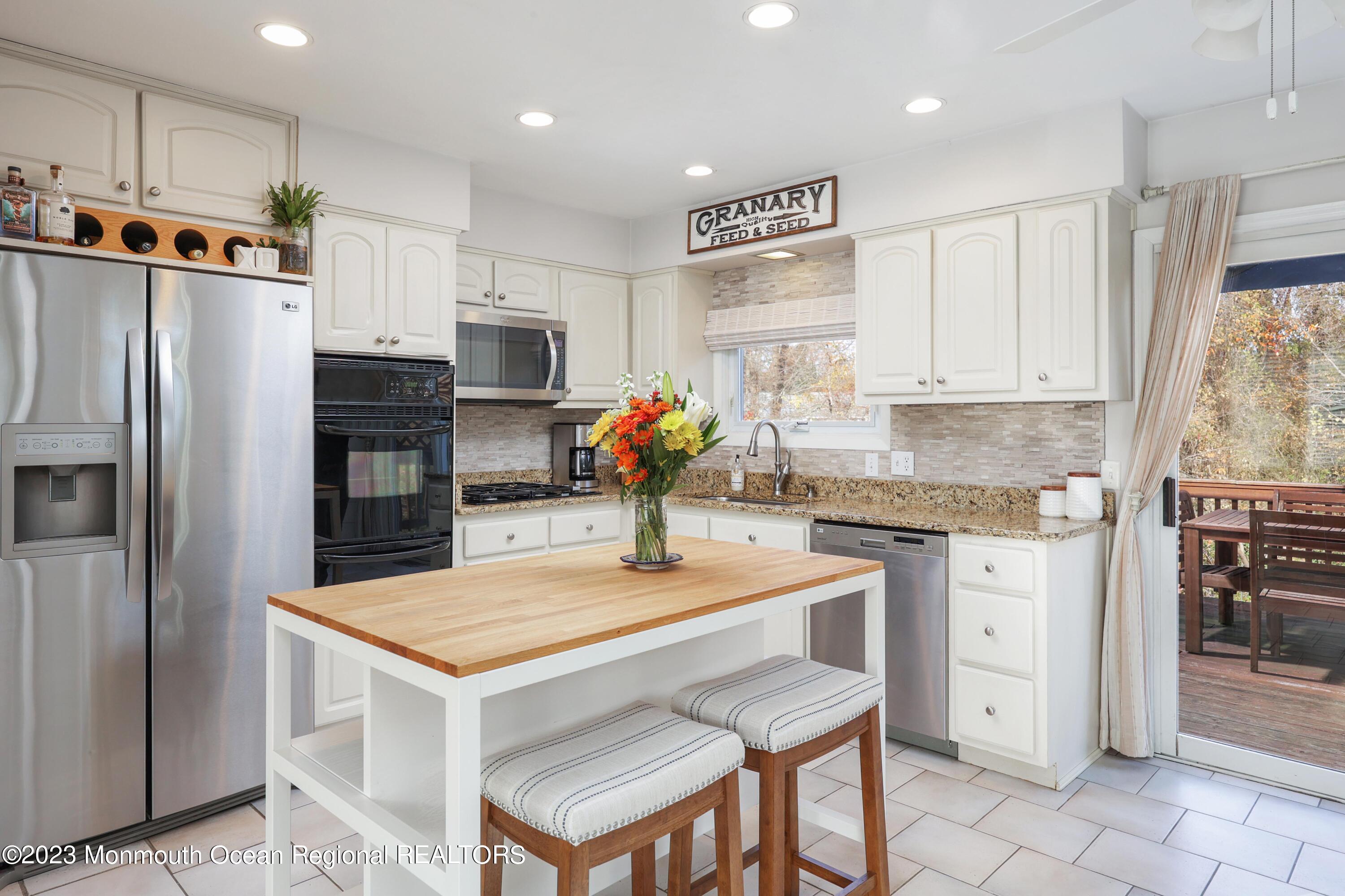 1208 Oak Road Manasquan, NJ 08736 - Photo 17 of 52 a kitchen with stainless steel appliances granite countertop a table chairs sink refrigerator and microwave