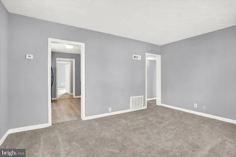 a view of an empty room with closet and a window