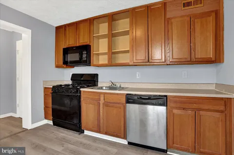 a kitchen with granite countertop wooden cabinets and a stove top oven