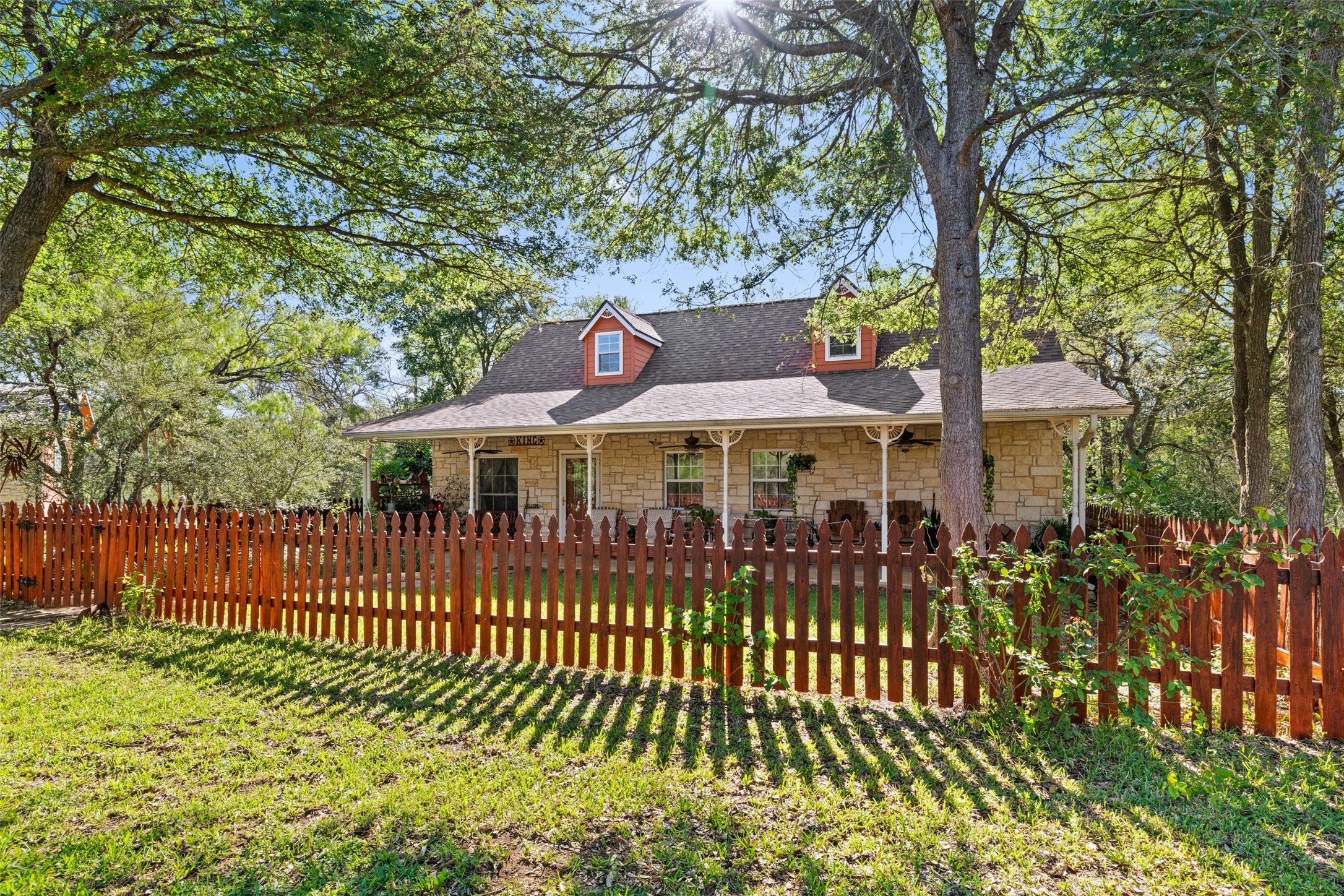 399 Upper Elgin River Road Elgin, TX 78621 - Photo 5 of 39 Cape cod home with stone siding, covered porch, a fenced front yard, and roof with shingles