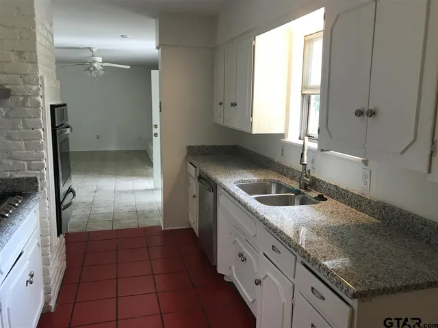 a kitchen with granite countertop a sink stove and refrigerator