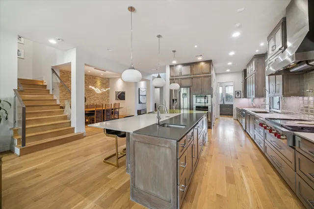 a kitchen with stainless steel appliances granite countertop a sink a stove and a wooden floors