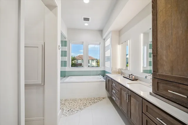 a bathroom with a double vanity sink a mirror and a bathtub