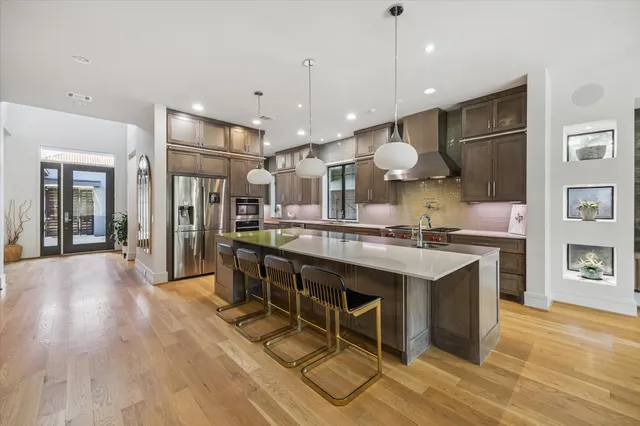 a kitchen with stainless steel appliances granite countertop a sink a stove and a wooden floors