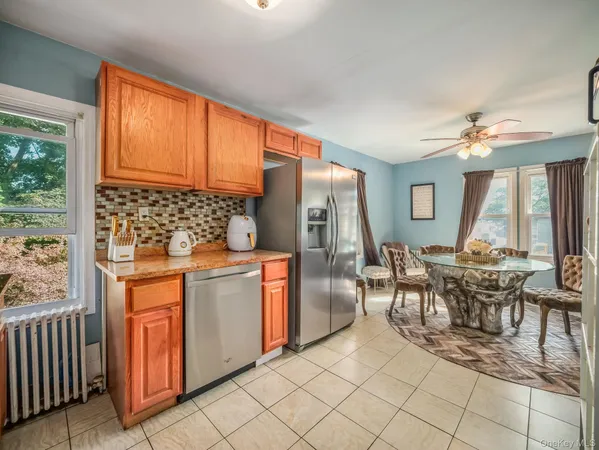 a kitchen with stainless steel appliances granite countertop a stove a refrigerator a dining table and chairs