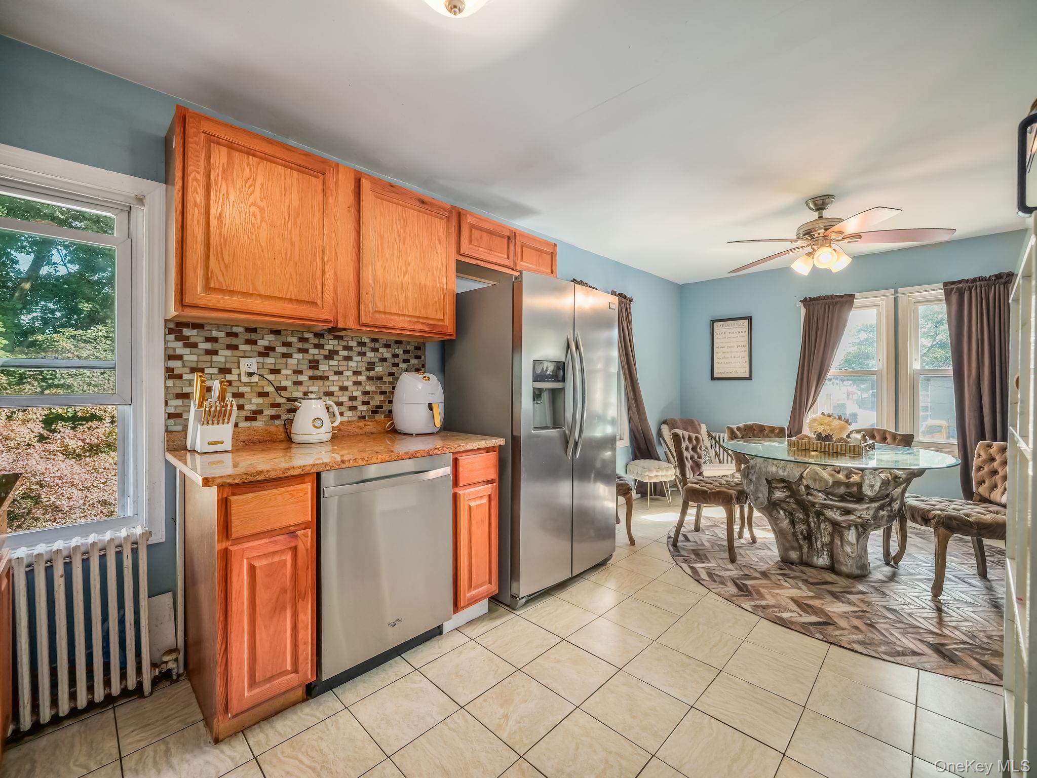 3 South Myrtle Avenue Spring Valley, NY 10977 - Photo 14 of 40 Kitchen featuring radiator heating unit, stainless steel appliances, backsplash, and brown cabinetry