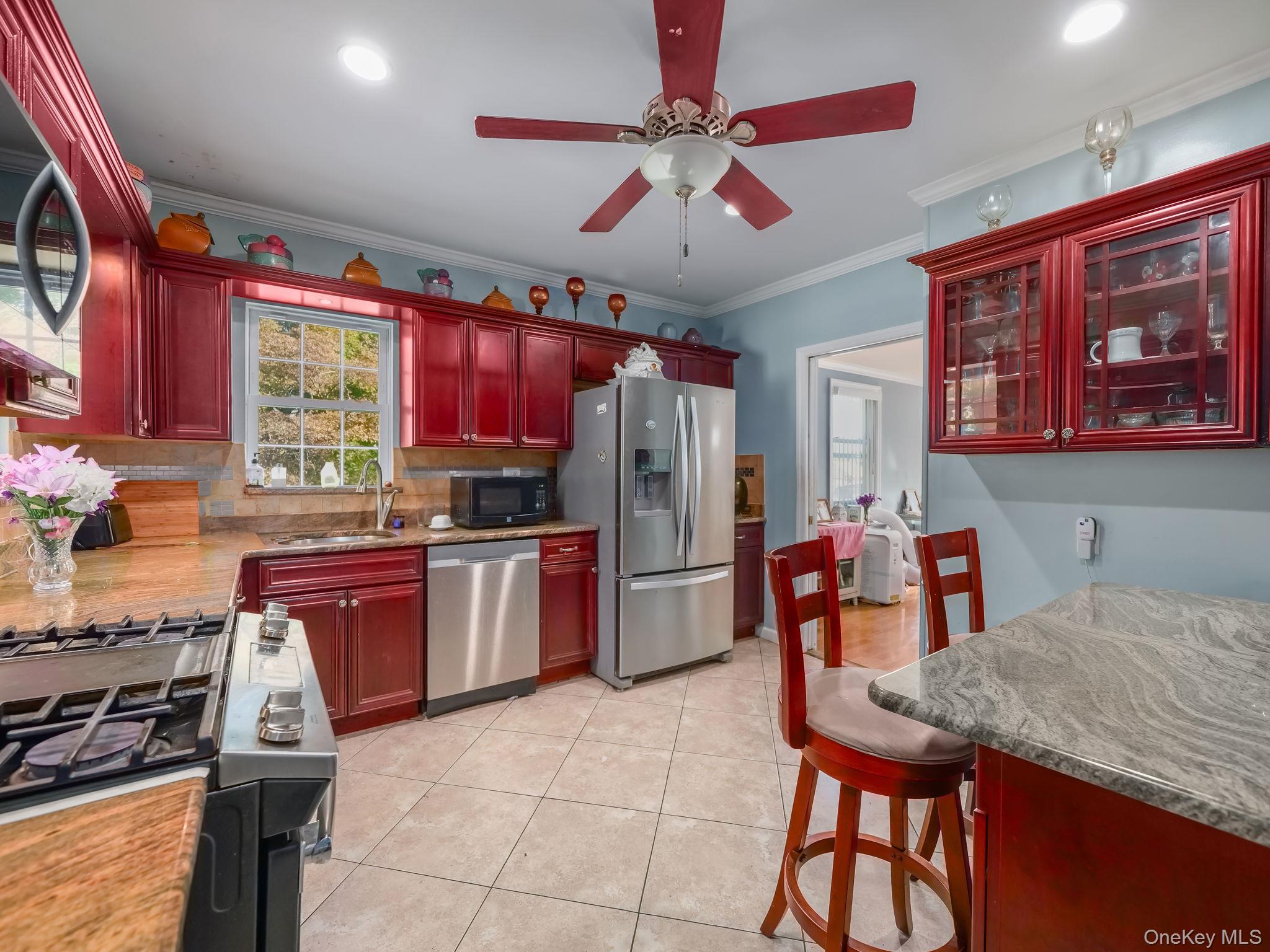 3 South Myrtle Avenue Spring Valley, NY 10977 - Photo 21 of 40 Kitchen featuring reddish brown cabinets, backsplash, appliances with stainless steel finishes, ornamental molding, and a ceiling fan