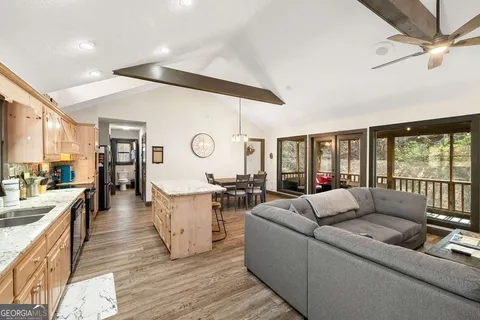 a living room with couches and kitchen view with wooden floor