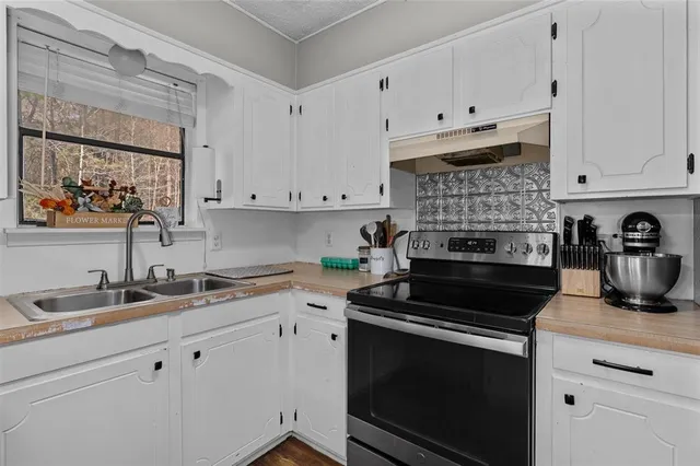 a kitchen with granite countertop white cabinets and black appliances