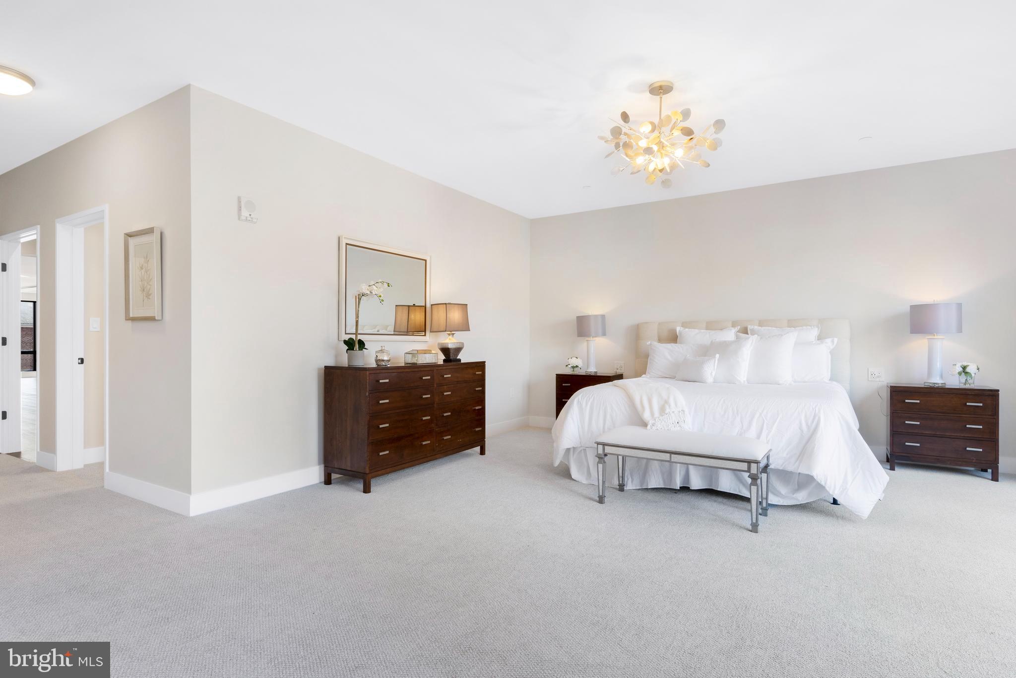 427 East Lancaster Avenue, Unit 2201 Wayne, PA 19087 - Photo 28 of 46 a spacious bedroom with a bed and a chandelier