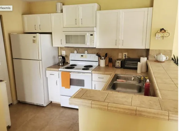 a kitchen with white cabinets and white appliances