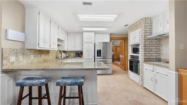 a large kitchen with granite countertop a sink and cabinets